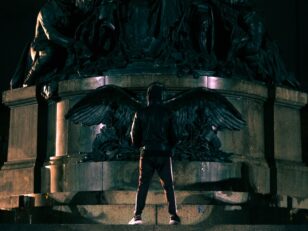 man in black jacket and pants standing beside black statue