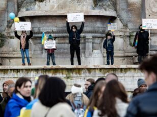 a group of people holding signs in front of a fountain