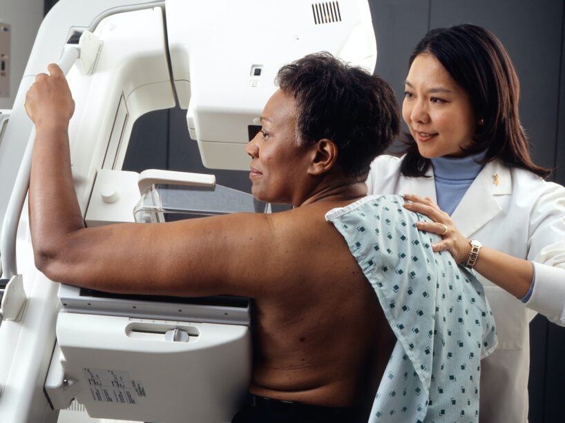 female doctor standing near woman patient doing breast cancer screening